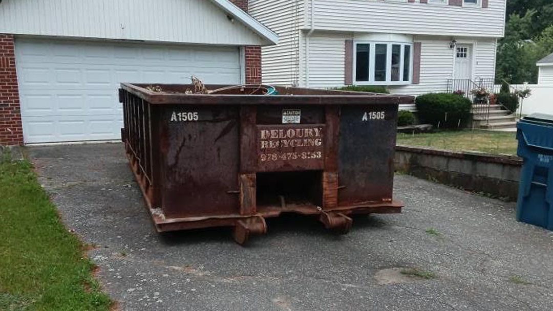 A 15-yard dumpster loaded with backyard debris, old fencing, and outdoor junk in 01876